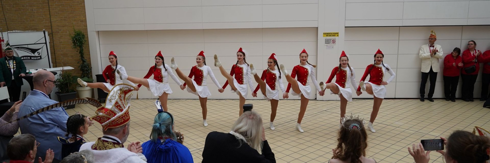 Eine Gruppe von Frauen in traditionellen Kostümen bei einer feierlichen Veranstaltung in einer Halle.